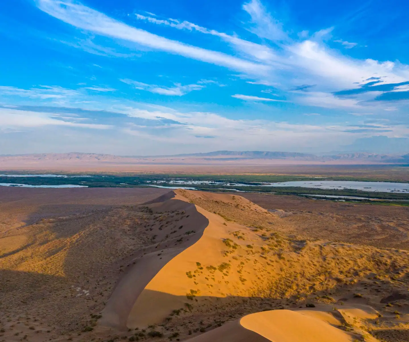 Aerial view of the Singing Dune ridge with the Ili River wetlands stretching to the horizon